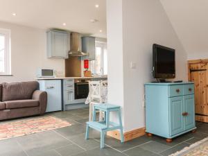 Una cocina con un taburete azul y un televisor sobre un mueble. en Hill Coach House, en Watchet
