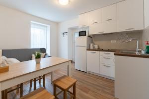 a kitchen with white cabinets and a wooden table at Tramontana and Maestral in Izola