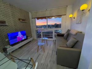 a living room with a couch and a flat screen tv at El Atardecer Skyline romantic views in Málaga