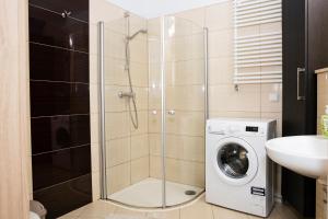 y baño con ducha de cristal y lavadora. en Olympic Park, en Kołobrzeg