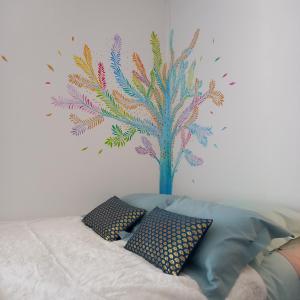 a bedroom with a mural of a tree on the wall at Chambres d'Hôtes Couleurs d'Elvine in Coutances