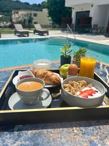 a tray of breakfast food on a table next to a pool at Κimiro Hotel Tsilivi in Plános