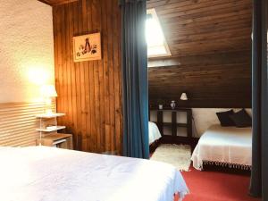 a bedroom with two beds and a wooden wall at La bergerie d'Egat: Chalet authentique avec vue in Égat