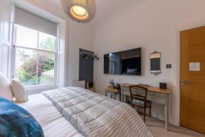 a bedroom with a bed and a desk and a window at Annandale Guest House in St. Andrews