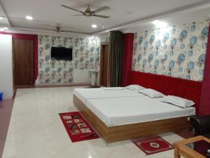 a bedroom with a large white bed and a tv at Hotel Geetanjali Buddha Resort By WB Inn in Bodh Gaya