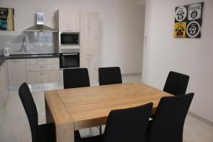 une cuisine avec une table en bois et des chaises noires dans l'établissement Seaside Accomodation, à Marsaskala