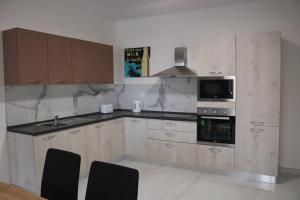 une cuisine avec des armoires en bois et un four à plaques de cuisson dans l'établissement Seaside Accomodation, à Marsaskala