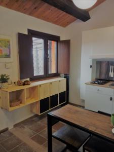 cocina con armarios de madera, mesa y ventana en Agriturismo Becerca Vegan en Serra San Quirico