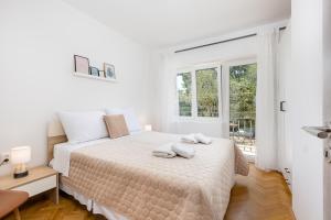 a white bedroom with a bed with towels on it at Apartment Ana in Vantačići