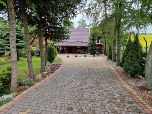 a brick walkway leading to a house with trees at Wilkiejmy wieś in Jeziorany