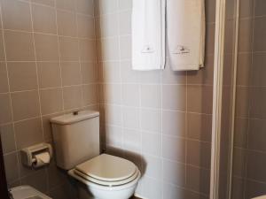 a bathroom with a toilet and towels on the wall at Casa do Pontelhão Serra d'Arga in Arga de Cima