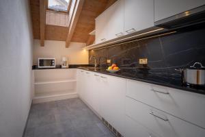 a kitchen with white cabinets and a black counter top at Apartments Lasteis in La Villa