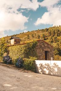 a stone building with flowers on the side of a road at Moinho d'Antoninha in Leomil