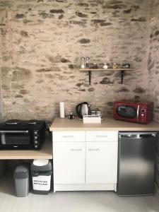 a kitchen with a microwave, sink, and refrigerator at Maison De Vacances A Brambuan in Josselin