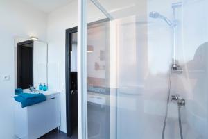 a white bathroom with a shower and a sink at Résidence Nemea Villeneuve Métropole in Villeneuve d'Ascq