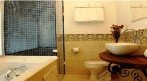 a bathroom with a toilet, sink and tub at Lis Bleu Pousada in Tiradentes