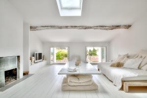 Biały salon z białą kanapą i kominkiem w obiekcie Le Cocon en plein centre du village médiéval de Mougins vue mer w mieście Mougins