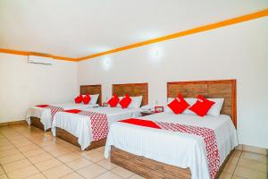 Habitación con 3 camas con sábanas rojas y blancas. en OYO Hospedaje Colibri en Chiapa de Corzo