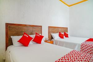 2 camas en una habitación con almohadas rojas. en OYO Hospedaje Colibri en Chiapa de Corzo