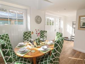 a dining room with a wooden table and green chairs at Chestnut Cottage in Sheffield