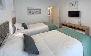 ein Hotelzimmer mit zwei Betten und einem Fernseher in der Unterkunft Casa AL Reis in Faro