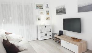 ein weißes Wohnzimmer mit einem TV und einem weißen Sofa in der Unterkunft Casa AL Reis in Faro