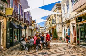 eine Gruppe von Menschen, die an Tischen in einer Straße sitzen in der Unterkunft Casa AL Reis in Faro