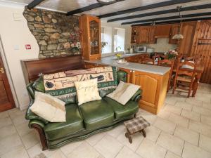 a living room with a green couch and a kitchen at Y Cartws in Llandysul