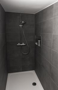 a bathroom with a shower with black tiles at Hinterm Marstall 2 in Coburg