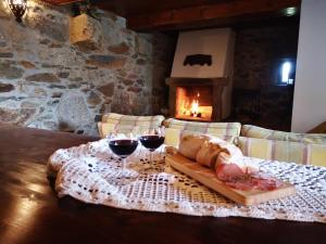 a table with wine glasses and bread and a fireplace at Casa do Pontelhão Serra d'Arga in Arga de Cima