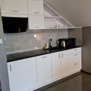 a kitchen with white cabinets and a black counter top at Apartament Wileńska in Mikołajki