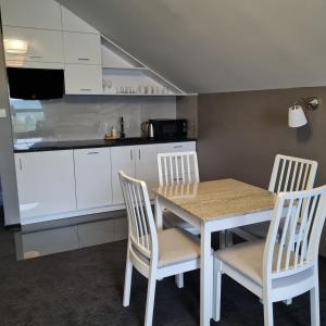 a kitchen with white cabinets and a table and chairs at Apartament Wileńska in Mikołajki