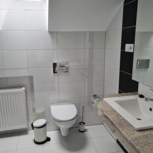 a white bathroom with a toilet and a sink at Apartament Wileńska in Mikołajki