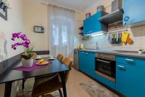 eine Küche mit blauen Schränken und einem schwarzen Tisch in der Unterkunft Apartman Kortil in Rijeka