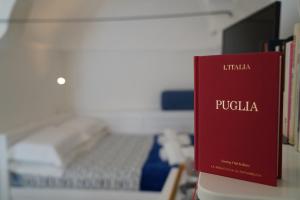 a red book sitting on a desk next to a bed at CasaBella - con TERRAZZA PANORAMICA in Ostuni +58 photos