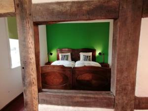 sypialnia z drewnianym łóżkiem i zieloną ścianą w obiekcie Bruchmühlen w mieście Bruchhausen-Vilsen