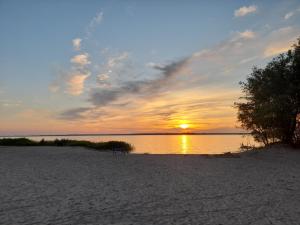 a sunset on a beach with the sun setting at Ferienhaus Kranichhorst - Exklusiv-Nutzung mit großem Garten und Strandnähe in Bodstedt +7 photos