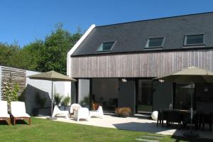 patio z białymi krzesłami, stołami i parasolami w obiekcie Maison de vacances Lesconil à 500 m de la plage w mieście Plobannalec-Lesconil