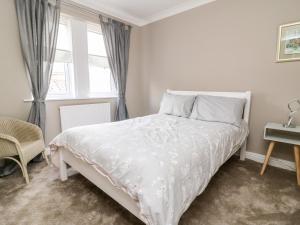 a bedroom with a white bed and a window at 8 Williamson Drive in Ripon