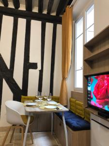 ein Esszimmer mit einem Tisch und einem TV in der Unterkunft A 2 Pas de Panthéon Quartiers Latins in Paris
