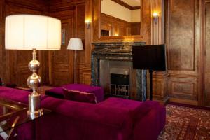 a living room with purple furniture and a fireplace at Hotel New York by WestCord in Rotterdam
