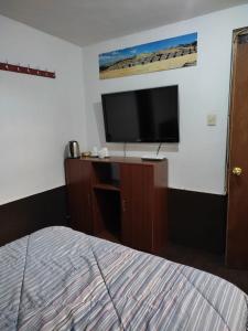 a bedroom with a bed and a flat screen tv at Coronado1936 in Cusco