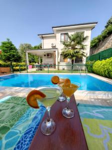 two martini glasses on a table next to a swimming pool at family villas sapanca in Sapanca