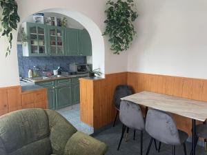 Jóbarát vendégház في Sáta: مطبخ مع دواليب خضراء وطاولة وكراسي خشبية