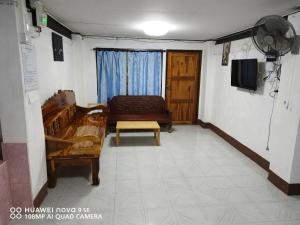 a living room with a couch and a tv at โฮมสเตย์เรือนเจ้าจอม in Ban Bo Hin