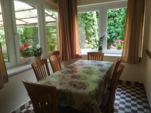 a dining room with a table and chairs and windows at Evelin vendégház in Bogács