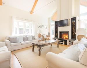 a living room with white furniture and a fireplace at Ragleighs in Polzeath