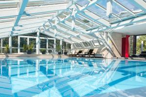 a swimming pool with a glass ceiling and blue water at Hotel-Restaurant Schwedi in Langenargen
