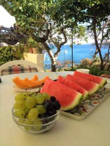 una mesa con una bandeja de fruta y un tazón de uvas en Sea View Room Macolic, en Rab