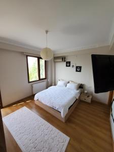 a bedroom with a white bed and a flat screen tv at family villas sapanca in Sapanca